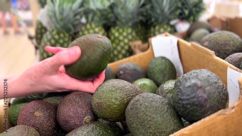 Shopper Selecting Fresh Avocado in Supermarket Produce Aisle