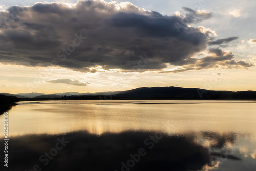 Serene Lake Reflection During Sunrise with Dramatic Summer Clouds
