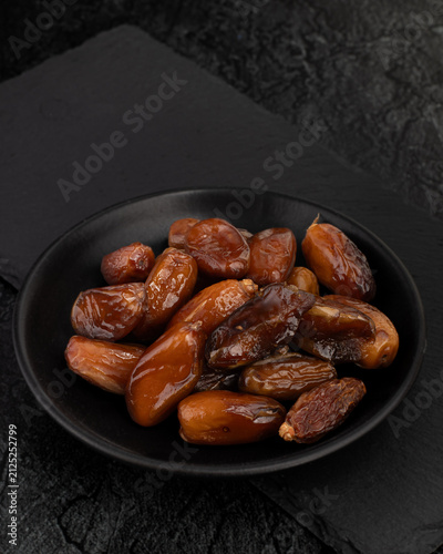 Fresh Dates in Black Bowl on Dark Stone Background