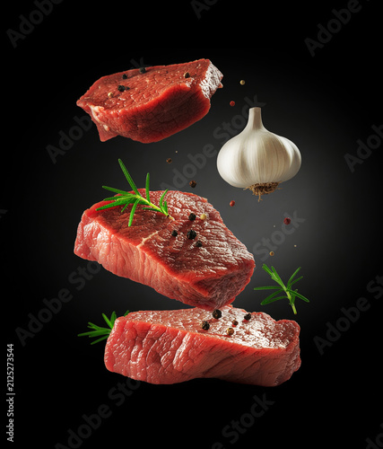 Beef steaks with rosemary and garlic in the air on black background. Generative AI