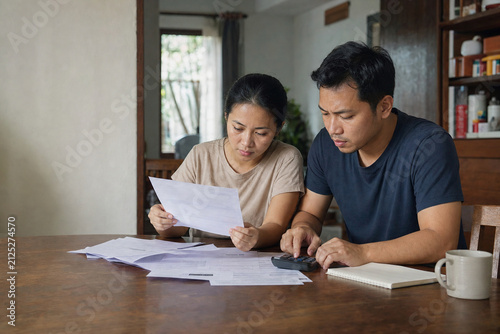Asian couple reviewing household bills and calculating monthly expenses