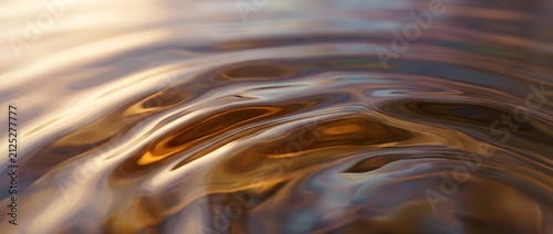 Ripples on surface of liquid water with golden sunset reflections