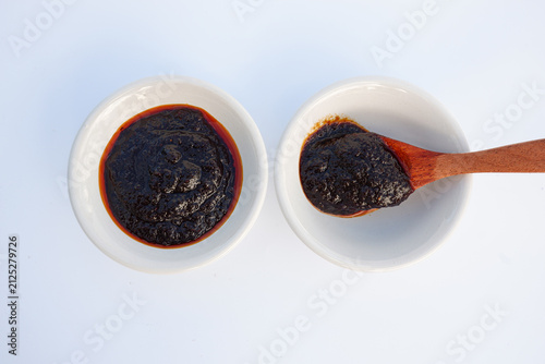 Two small white bowls of Thai chili paste with a wooden spoon, top view isolated on white background