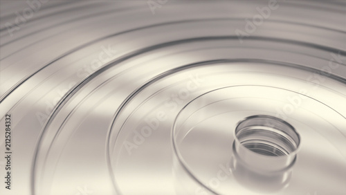 Smooth circular rings made of clear glass reflect light on a bright surface creating a clean and modern geometric pattern, abstract background