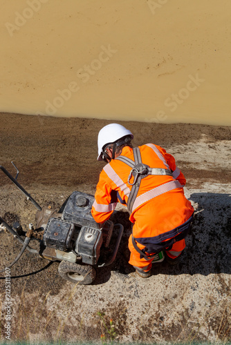 Ouvrier travaillant avec une pompe au bord de l'eau