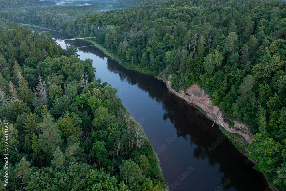 Fototapeta premium Aerial view of Velnala sandstone cliffs and the Gauja River at sunrise in Gauja National Park, Sigulda, Latvia