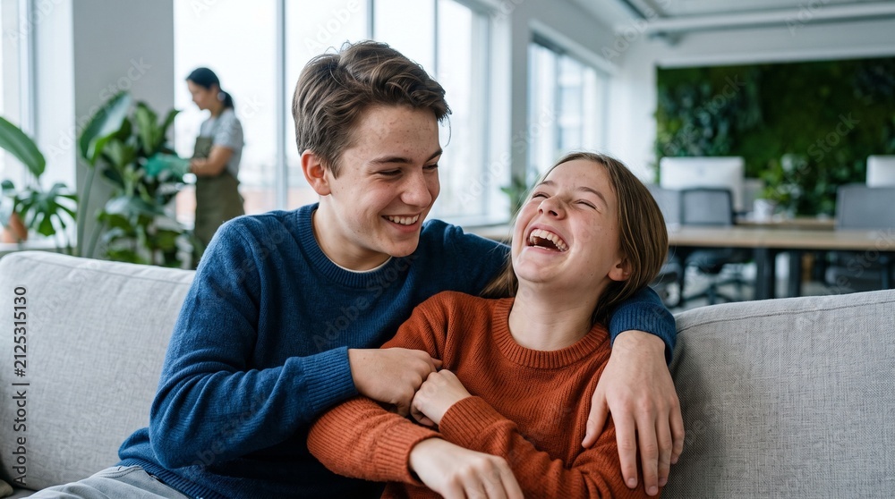 Fototapeta premium Joyful teenage siblings share a laugh while relaxing on a couch in a modern office setting