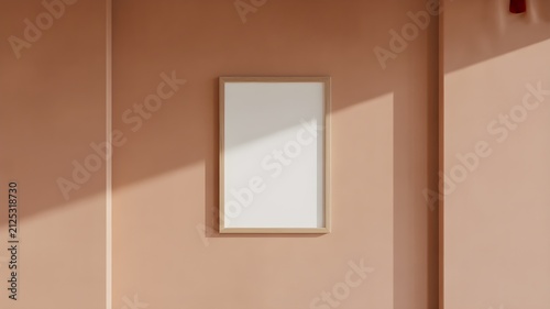 Empty vertical wooden picture frame on a solid terracotta colored wall with soft sunlight and shadows