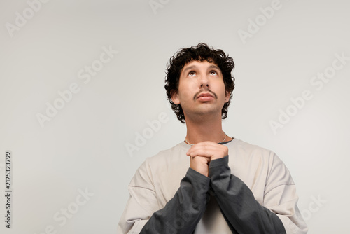 Fotografie Young man with moustache gazes upwards in thoughtful contemplation