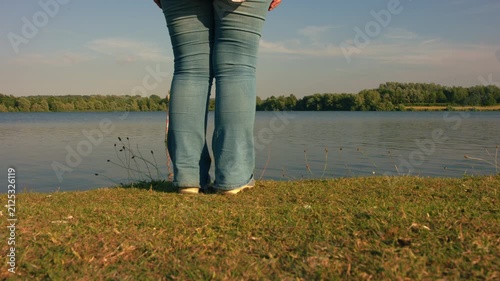 Woman by lake side with summer meadow flowers