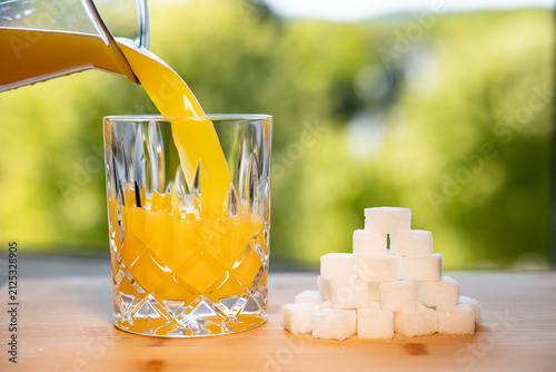 Canvastavla A carafe pours fresh orange juice into a glass next to a stack of sugar cubes, a sweet, refreshing drink