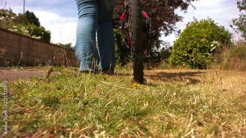 Cyclist walking with bicycle on grass path