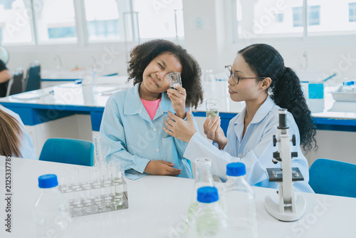Фотография Happy girl student showing cheerful smile with classmate in school science labor