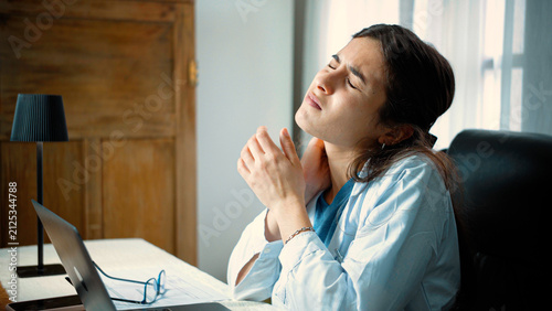 Bild auf Leinwand Young Latina female nurse experiencing significant neck pain from poor posture w