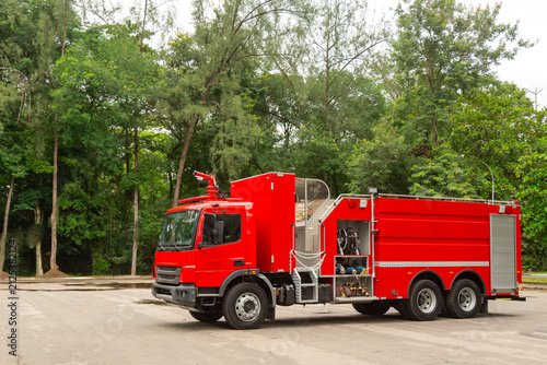 Caminhão de bombeiros vermelho estacionado em área aberta cercada por árvores