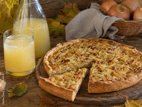 Knuspriger Zwiebelkuchen mit Federweißer auf rustikalem Holztisch. Klassische deutsche Herbstspezialität zur Weinlese mit regionaler Tradition und saisonalem Genuss.