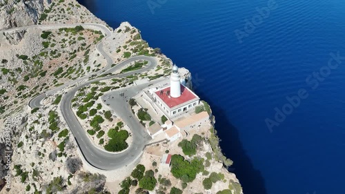 Aerial forward flyover shot approaching Cap de Formentor lighthouse and winding road in Mallorca