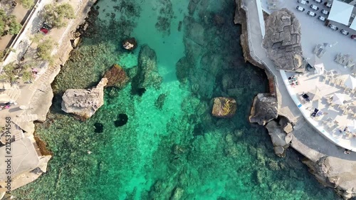 Top down aerial ascending shot over crystal clear turquoise cove water and rocky seabed in Cala Sant Vicenc, Mallorca