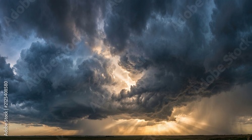 Dramatic stormy sky with dark heavy clouds and golden sunlight breaking through at sunset