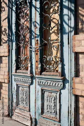 Vintage double wooden door with ornate ironwork chained and weathered facade