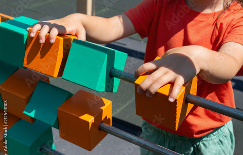 Close-up of children's hands turning over colorful cubes on the playground. Fine motor skills concept. Educational games outdoors.