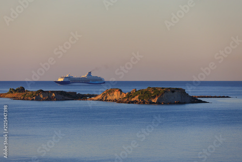 A photo of a large cruise ship sailing in the Ionian Sea past an island off the coast of Greece