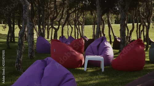 A seating area of soft seats is located in the shade of pine trees in the park