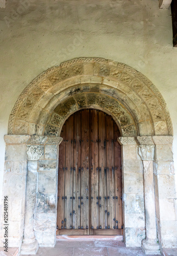 Foto Carved stone portal with decorated semicircular arch and wooden door at the 12th