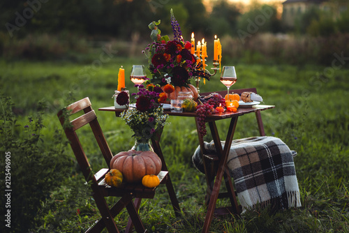 Fall table decoration with pumpkin composition. Family cozy thanksgiving dinner arrangement outdoors, in a garden, elegant wedding decor. Countryside style, rose wine, cheeseboard, fruits, autumn mood