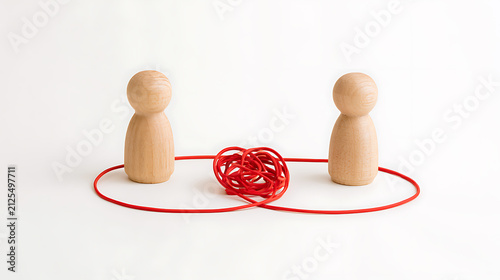 Two wooden peg figures connected by a tangled red string, symbolizing complex relationships, communication challenges, or problem-solving