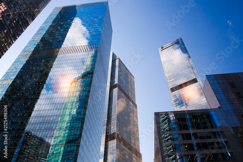 Photography Tall glass skyscrapers of business offices in city reflect blue sky, clouds, and other skyscrapers