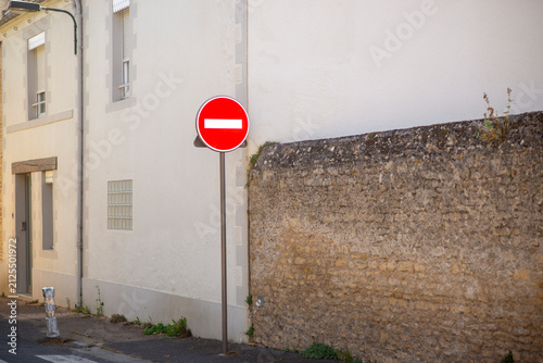 Urban street scene with no entry sign near historic stone wall