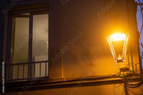 Urban night scene with illuminated streetlight and apartment window