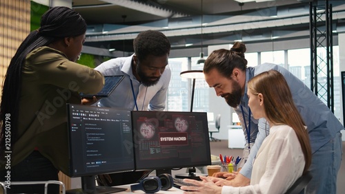 Fotografie Young developer asks colleagues for help after a corporate network attack, investigating unauthorized access alerts in a startup office
