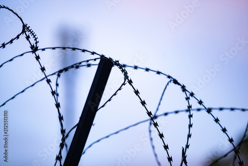 Obraz na plátně Silhouette of razor barbed wire fence against twilight sky background with copy