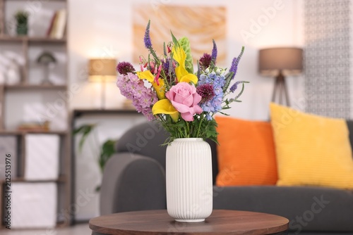 Bouquet of beautiful summer flowers in vase on wooden table indoors