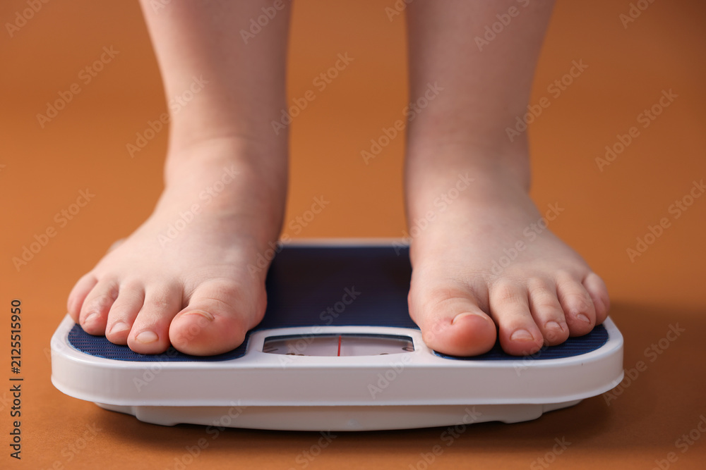 Fototapeta premium Overweight woman on scale against brown background, closeup