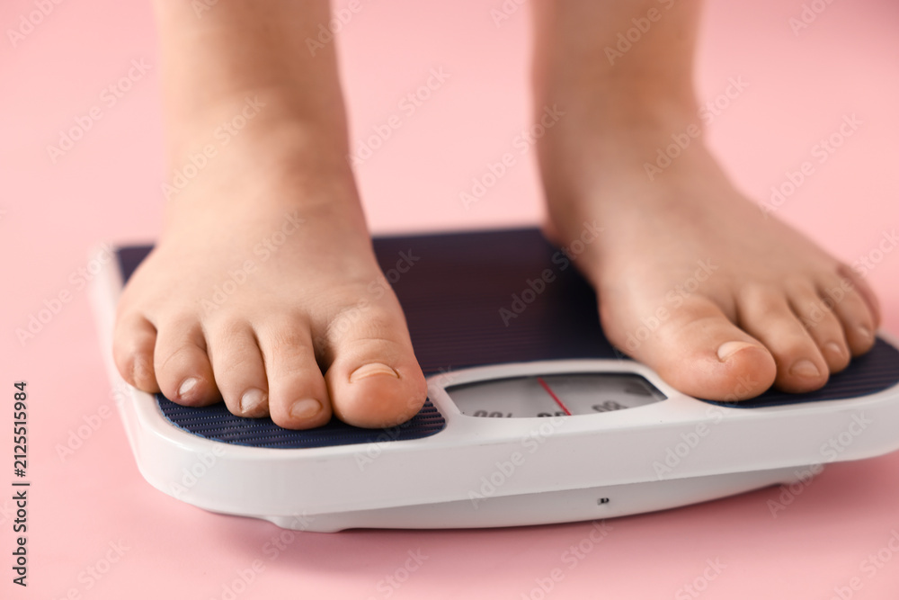 Fototapeta premium Overweight woman on scale against pink background, closeup