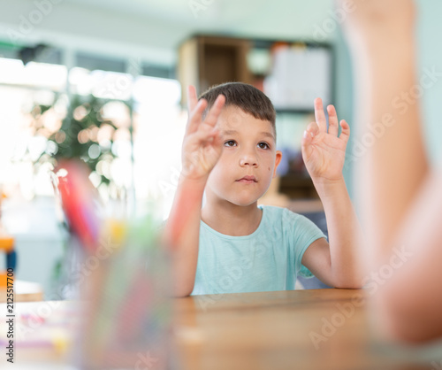 Canvas Print Boy makes movements with his fingers, repeats after teacher and performs tasks for fine motor skills
