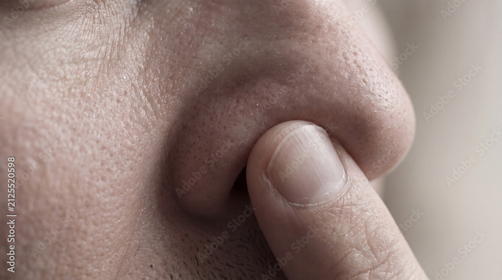 Fototapeta premium A high-detail close-up shot of a person’s finger gently touching or pressing against their nose, highlighting skin texture and pores.