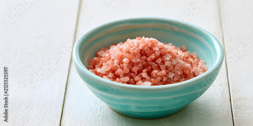 A turquoise bowl adorned with pink salt on a white surface