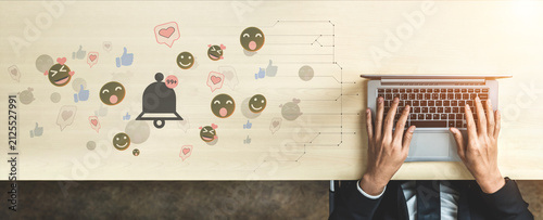 Cuadro en lienzo Hands of a Businessman Typing on a Laptop Surrounded by Emoji Reactions and Notification Icons Representing Digital Communication and Engagement