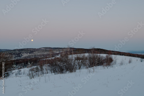 Konstfotografi winter moon in the mountains over snowy forest