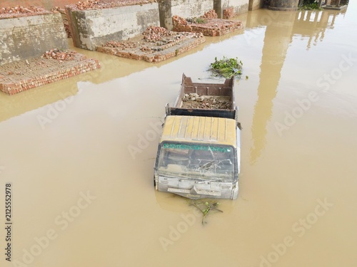Aerial view of a truck partially submerged in floodwater near brick structures in Chhagalnaiya, Chittagong Division, Bangladesh.
