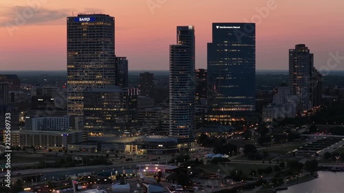 Aerial view of the Milwaukee, Wisconsin downtown skyline at dusk, showing illuminated skyscrapers along the Lake Michigan waterfront as the city lights turn