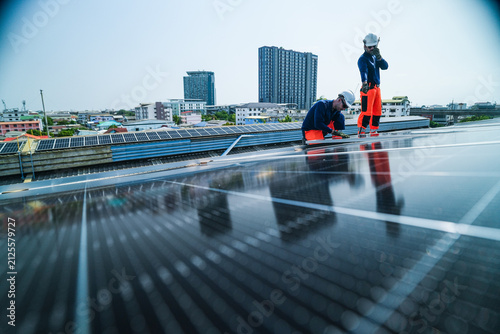 Foto A bearded engineer and his colleague in reflective vests and helmets confidently ease the panel down onto its clamps together on a large corrugated factory rooftop under the tropical sun