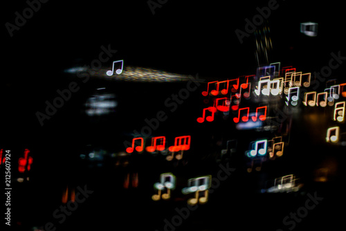Abstract musical note shaped bokeh lights with motion light streak on black background. Creative backdrop for music event, concert, podcast banner, and sound design.
