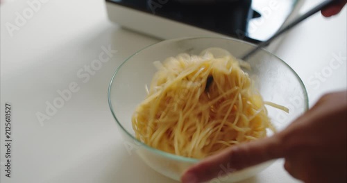 Close up of Asian Woman Hands Tossing Spaghetti Pasta in Bowl on Table,  Faceless Female Mixing Noodle Food Ingredient to Prevent Sticking in Kitchen Room, Home Cooking Concept.
