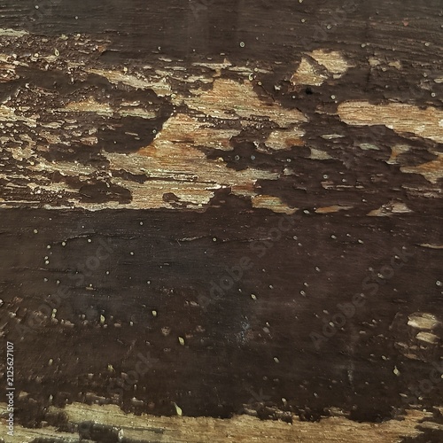 Close-up texture of weathered old dark brown wood surface with peeling paint and exposed grain.