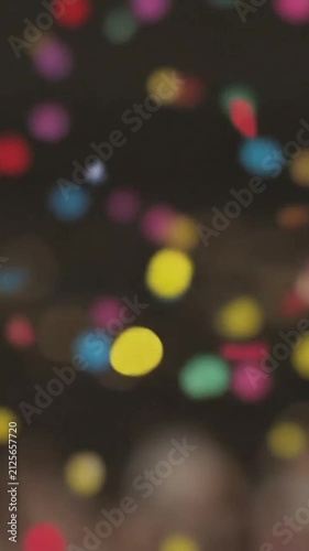Abstract background of colorful confetti falling slowly against a dark, out-of-focus backdrop.